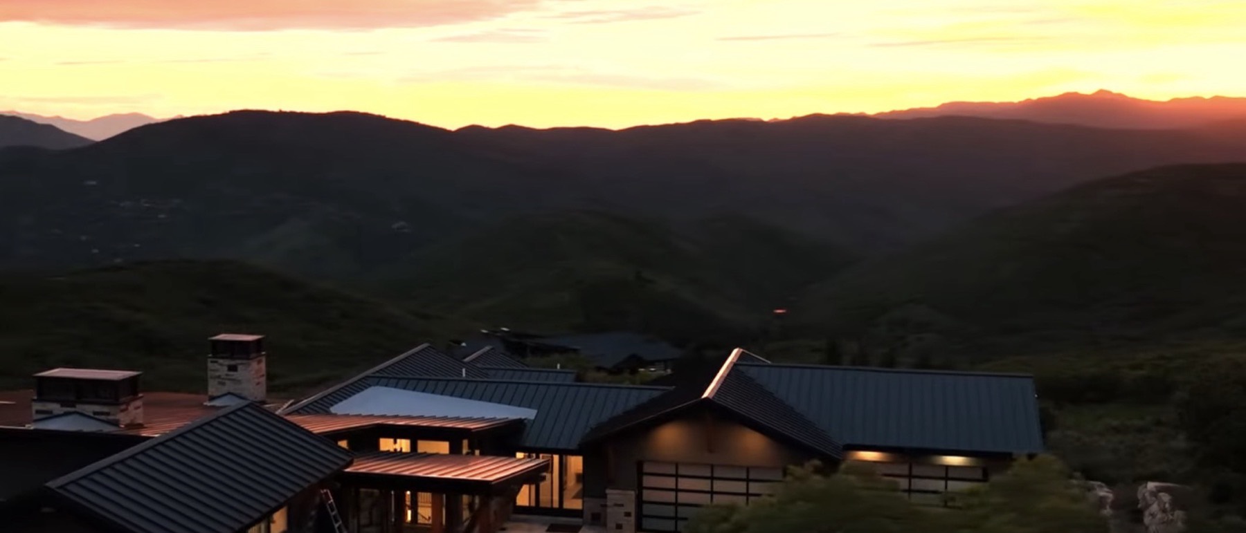 A mountain property at sunset, the valley falling away behind it