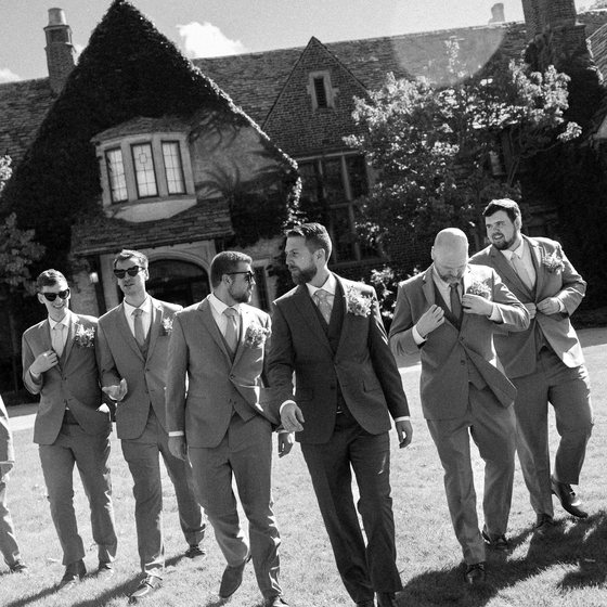 Groomsmen walking together outside a stone manor