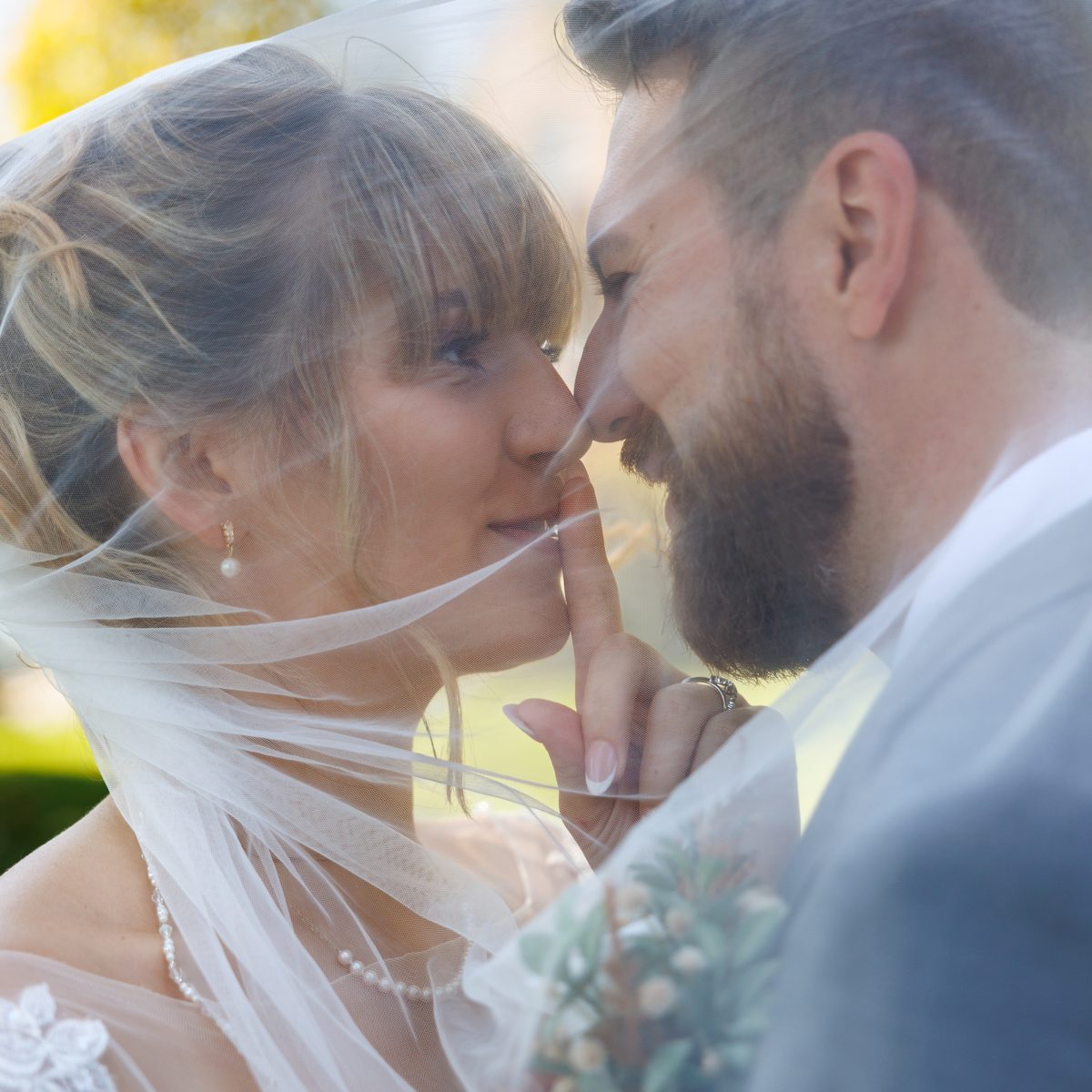 A bride and groom close together beneath her veil
