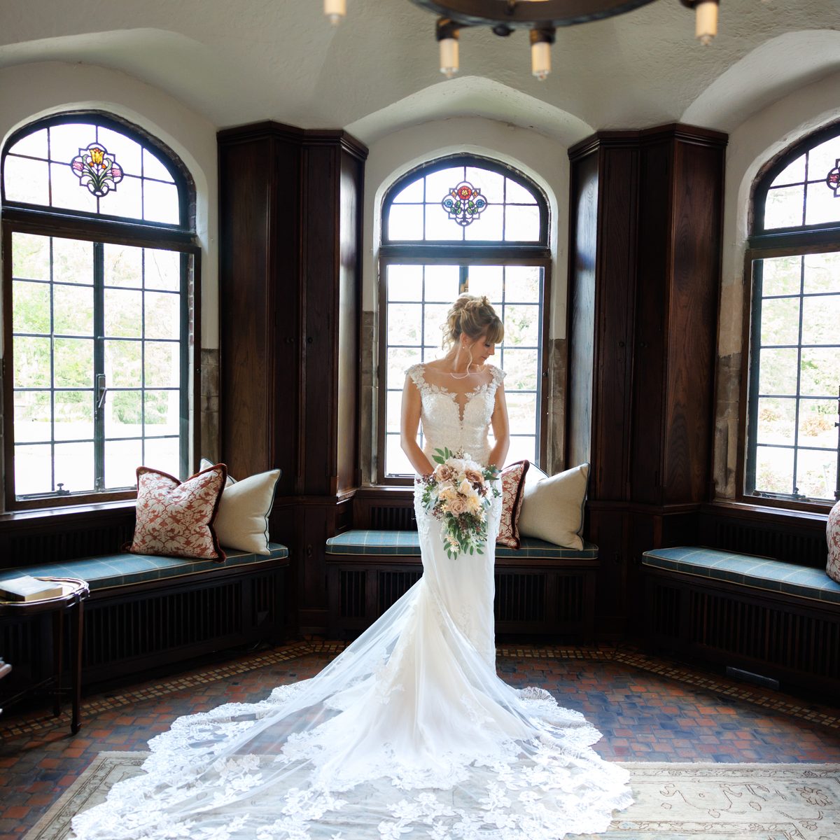 A bride's lace train spread across the floor of a stone bay window