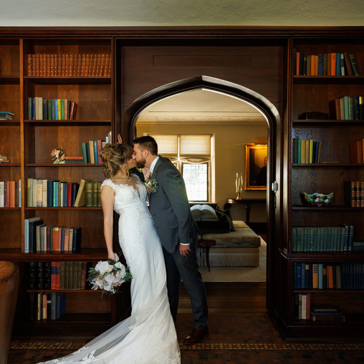 A couple kissing in the doorway of a wood-panelled library