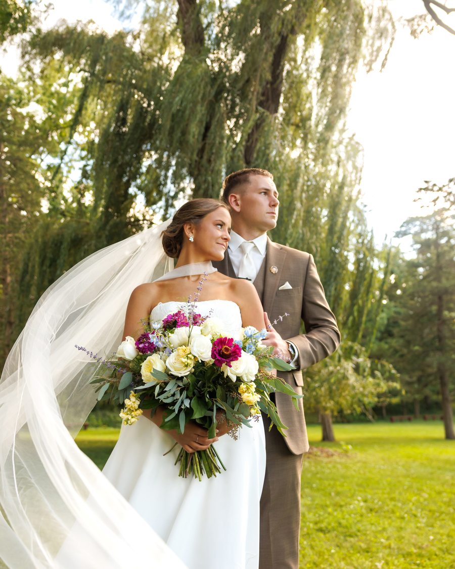A bride and groom together, her veil lifting in the breeze