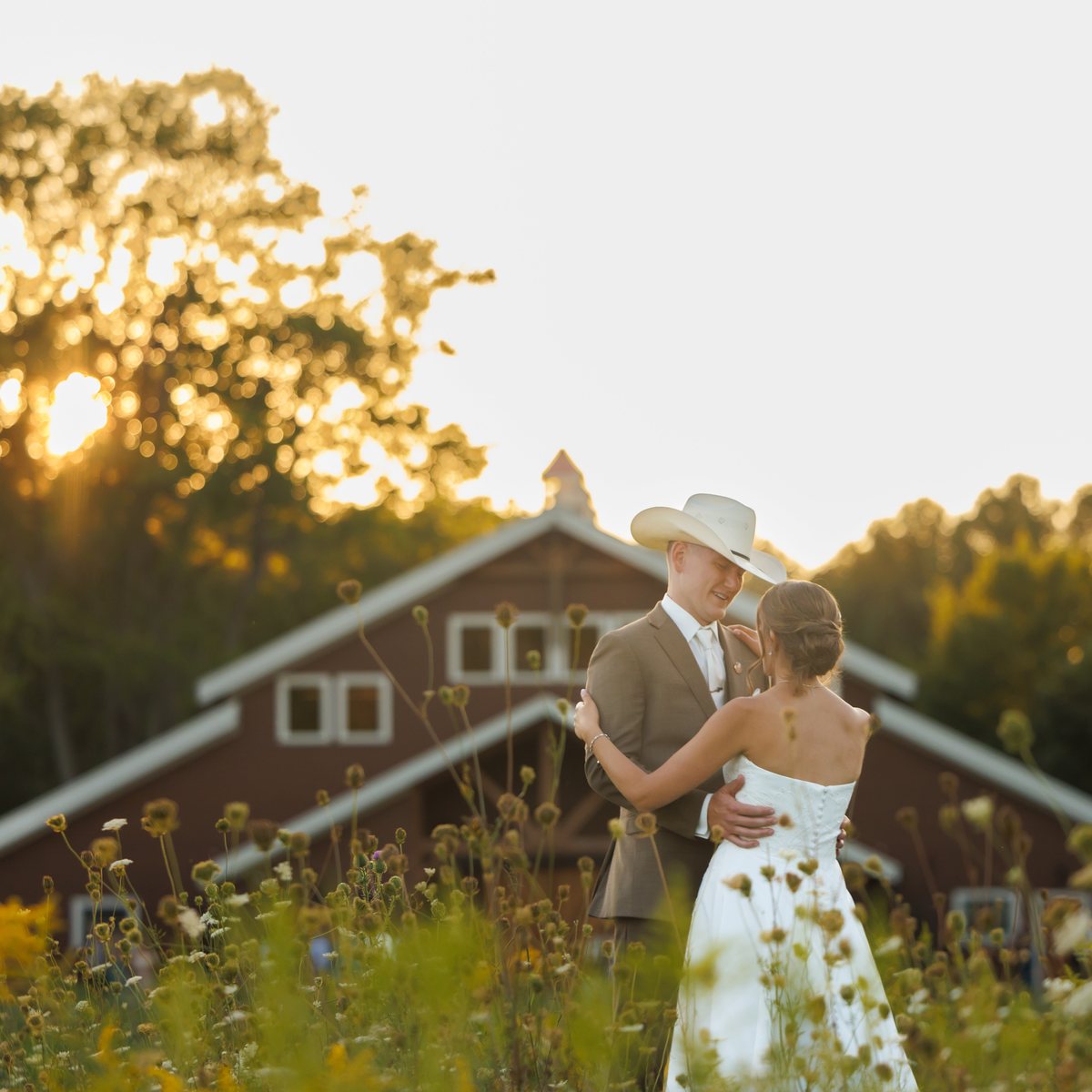 A couple at golden hour in front of a red barn