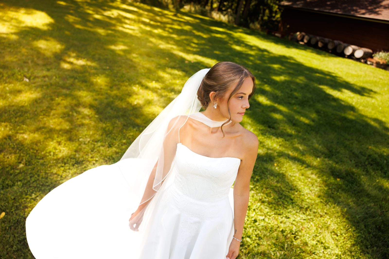 A bride in dappled afternoon light, her veil trailing behind her